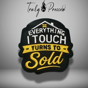 May include: Black embroidered patch with the text "EVERYTHING I TOUCH TURNS TO SOLD" in white and gold. The patch features a house graphic and is designed for real estate professionals.