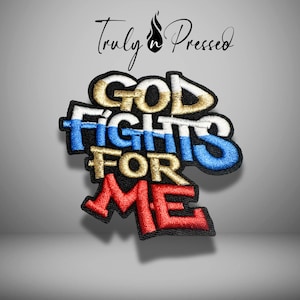 May include: Embroidered patch with the words "GOD FIGHTS FOR ME" in gold, blue, and red. The patch has a black border and the text "Truly n Pressed" in cursive script above the main text.