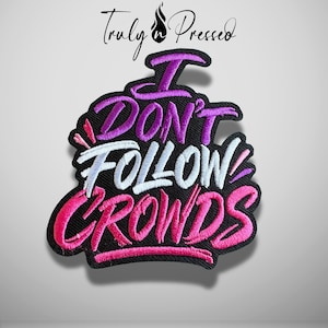 May include: An embroidered patch with a black background featuring the text Truly n Pressed at the top and the phrase I DON'T FOLLOW CROWDS in bold, stylized lettering. The words are stitched in vibrant shades of purple, white, and pink.