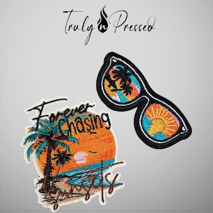 May include: Two embroidered patches featuring a tropical theme. One patch is circular with a palm tree, ocean, and sunset, with the text "Forever Chasing Sunsets." The second patch is shaped like sunglasses with reflections of palm trees and a sun.