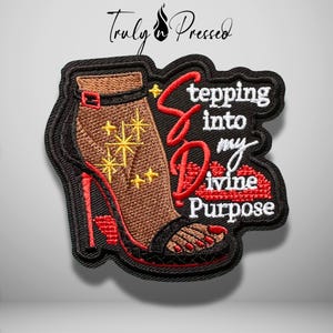 May include: An embroidered patch featuring a brown high-heeled sandal with yellow star accents. The text reads Stepping into my Divine Purpose in white and red thread. The design includes a red lip graphic and a black border outline.
