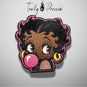 May include: An embroidered patch featuring a cartoon character with black hair, gold hoop earrings, and a bright pink bubblegum bubble. The design is outlined in pink thread and includes the text Truly n Pressed at the top.