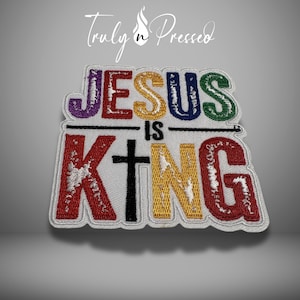 May include: Embroidered patch with the words "JESUS IS KING" in colorful letters. The patch features a cross and is outlined in white. The brand name "Truly n Pressed" is at the top.