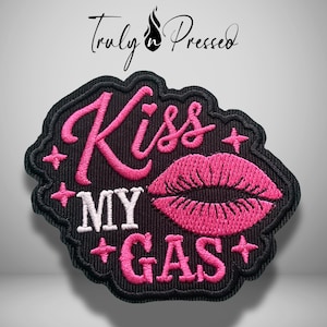 May include: A black embroidered patch featuring the pink text Kiss, the white text MY, and the pink text GAS. The design includes a pair of pink embroidered lips and four small pink star accents. The patch has a black stitched border.