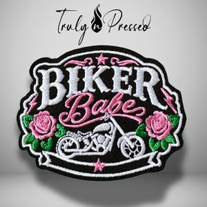 May include: Black embroidered patch with the words "BIKER Babe" in white and pink script, featuring a motorcycle and pink roses. The patch has a black border and the text "Truly Pressed" in cursive.