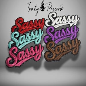 May include: Embroidered patches in various colors, each spelling "Sassy" in a cursive font. Colors include red, teal, pink, white, purple, and brown, with a glittery black border. The brand name "Truly Pressed" is at the top.
