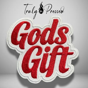 May include: An embroidered patch featuring the red text Gods Gift in a cursive font with a white border. Above the patch, the black text Truly n Pressed is displayed with a small flame icon positioned between the two words on a light background.