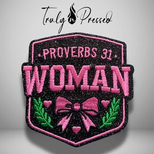 May include: A black glittery shield-shaped embroidered patch featuring the pink text PROVERBS 31 WOMAN. The design includes a pink bow, small pink hearts, and green leafy branches. Above the patch, the text Truly Pressed is visible in black.
