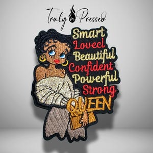 May include: Embroidered patch featuring a cartoon woman with blue eyes, gold earrings, and a gold-trimmed outfit. The patch includes the words "Smart, Loved, Beautiful, Confident, Powerful, Strong, QUEEN" in red and gold lettering. The patch is black with gold trim.