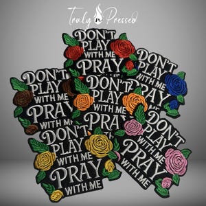 May include: Black embroidered patches with the phrases "DON'T PLAY WITH ME" and "PRAY WITH ME" in white script. Each patch is decorated with colorful embroidered roses in shades of red, orange, yellow, pink, and blue, with green leaves.