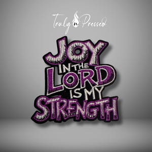 May include: Embroidered patch with the words "JOY IN THE LORD IS MY STRENGTH" in purple and white. The patch has a black border and the text is in a stylized font. The brand name "Truly n Pressed" is at the top.