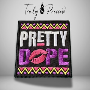 May include: A rectangular black embroidered patch featuring the white text PRETTY and purple text DOPE with a pink lip print replacing the letter O. The design includes yellow and pink zigzag borders at the top and bottom edges.