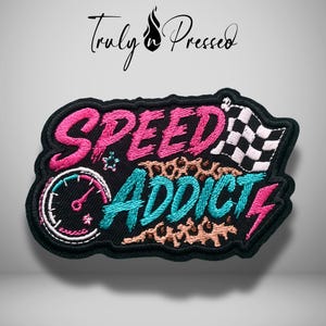 May include: An embroidered patch featuring the text SPEED ADDICT in pink and teal thread on a black background. The design includes a speedometer, a checkered flag, a lightning bolt, and leopard print accents. The text Truly n Pressed is above.