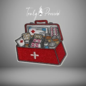 May include: Embroidered patch of a red first aid kit with a white cross on the front. The kit is open, revealing various pills, bandages, and medical supplies. The text "Truly n Pressed" is above the kit.