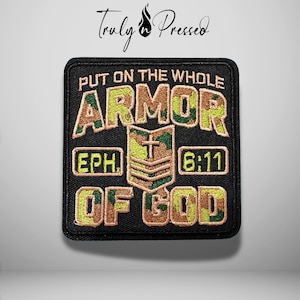 May include: A square embroidered patch with a black background featuring camouflage-patterned lettering that reads "PUT ON THE WHOLE ARMOR OF GOD" and "EPH. 6:11". A central camouflage shield icon displays a cross and three horizontal stripes.