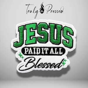 May include: An embroidered patch featuring the text "JESUS" in green with black outlines, "PAID IT ALL" in black, and "Blessed" in black script. The design includes small green star accents on a white background with a white border.