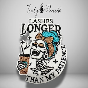 May include: An embroidered patch featuring a skeleton with teal hair and a brown bow, holding a brown coffee cup. The text reads LASHES LONGER THAN MY PATIENCE in black embroidery on a white background. The design includes small star accents.