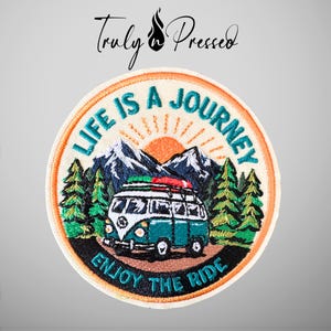 May include: A circular embroidered patch featuring a teal and white camper van on a road, surrounded by green pine trees and dark blue mountains under an orange sun. The text reads LIFE IS A JOURNEY and ENJOY THE RIDE in teal lettering.