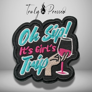 May include: A black embroidered patch with a scalloped edge featuring the text "Oh Sip! It's Girl's Trip" in teal and pink thread. The design includes an embroidered hand holding a wine glass filled with pink liquid and a black stem.