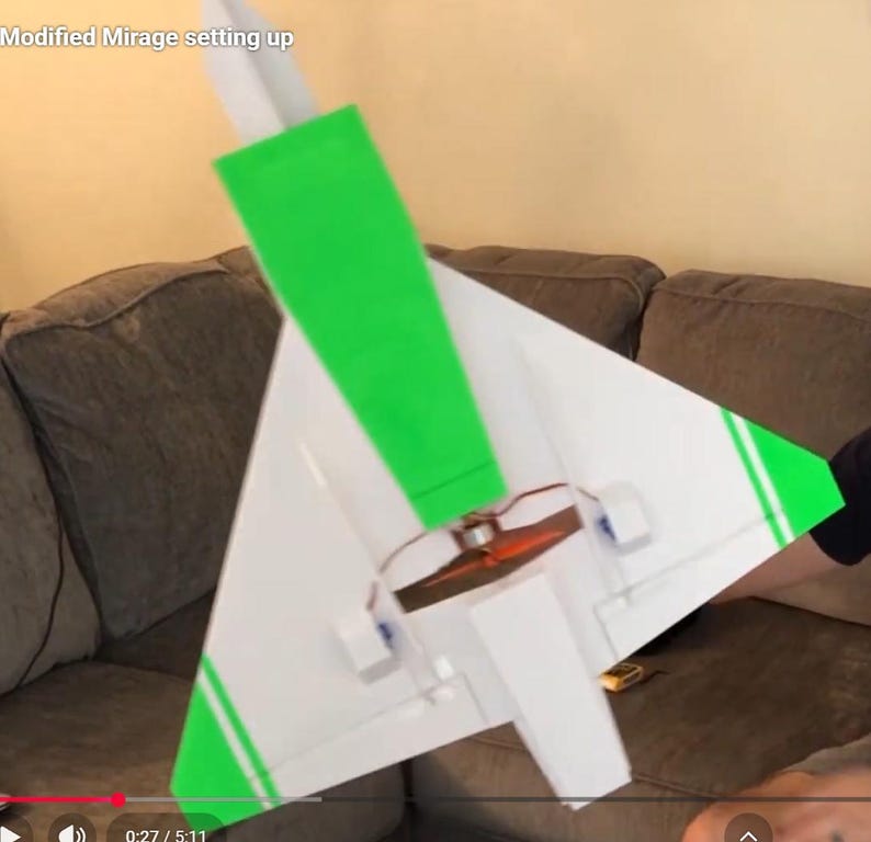 Peut inclure: Un mod&egrave;le d'avion blanc et vert avec le texte "Modified Mirage setting up". L'avion a un stabilisateur vertical vert et des accents verts sur les ailes. L'h&eacute;lice est visible.
