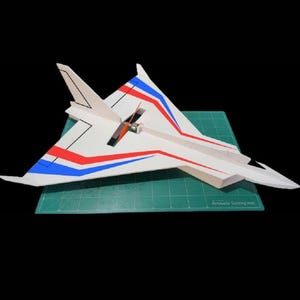 Peut inclure: Un mod&egrave;le d'avion blanc avec des rayures rouges et bleues sur les ailes et la queue. L'avion est pos&eacute; sur un tapis de coupe vert. Le mod&egrave;le a une h&eacute;lice et une conception d&eacute;taill&eacute;e.