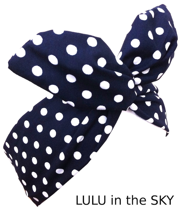 Peut inclure: Un bandeau bleu marine &agrave; pois blancs, nou&eacute; en un n&oelig;ud. Le bandeau porte l'inscription "LULU in the SKY" en lettres blanches.