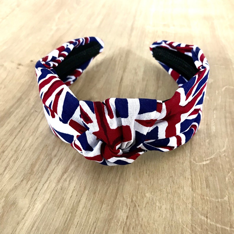 Puede incluir: Una diadema anudada con un patr&oacute;n de Union Jack en rojo, blanco y azul.