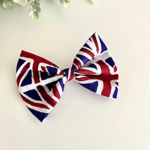 May include: A red, white, and blue bow tie with a geometric pattern. The bow tie is made of fabric and is tied in a knot.