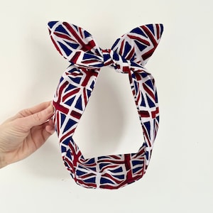 May include: A red, white, and blue headband with a Union Jack pattern. The headband is tied in a bow at the top.