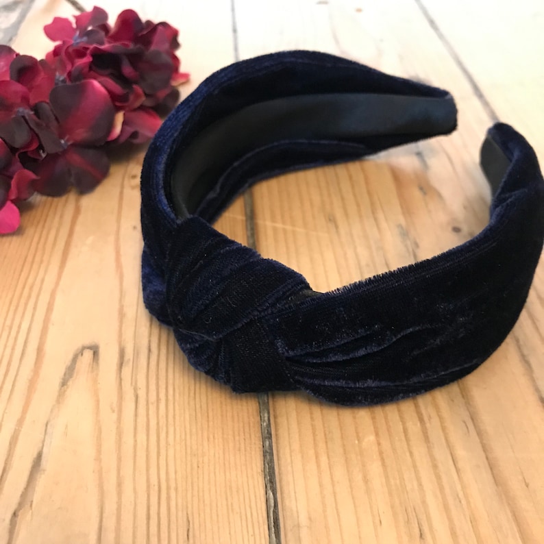 May include: A navy blue velvet knotted headband. The headband is made of a soft, stretchy material and has a comfortable fit.