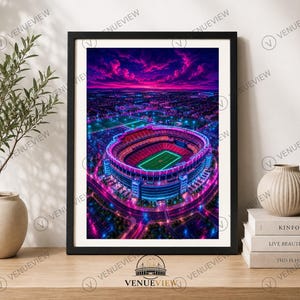 May include: A framed wall art print featuring an aerial view of a football stadium at night, illuminated by vibrant neon pink and blue lights under a dramatic purple sky. The stadium is surrounded by a city grid with glowing street lights.