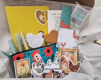May include: A stationery gift box containing a yellow notebook, a teal pencil case with a red flower and chicken pattern, a white chicken-shaped notepad, a small gold-toned picture frame with a chicken print, stickers, pens, and a book tracker card.