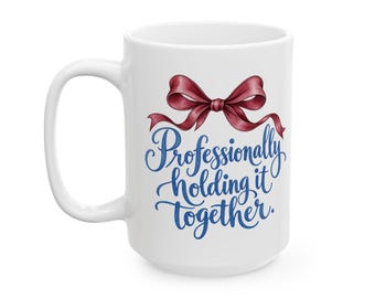 May include: A white ceramic mug featuring a dark red ribbon illustration at the top and the blue cursive text Professionally holding it together. The mug has a standard handle and a smooth, glossy finish on the exterior surface.