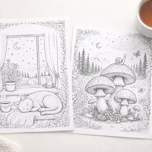 May include: Two black and white coloring book pages with nature scenes. One features a cat sleeping by a window, the other shows mushrooms and a snail. A cup of tea and a pen are also visible.