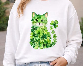 May include: White sweatshirt featuring a watercolor illustration of a green cat covered in shamrocks. The cat has green eyes and a pink nose. The word "White" is printed at the bottom. A St. Patrick's Day themed design.
