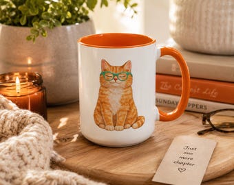 May include: A white ceramic mug with a bright orange interior and handle, featuring a graphic illustration of a seated orange tabby cat wearing green glasses. The cat has its eyes closed in a peaceful expression, centered on the front of the mug.