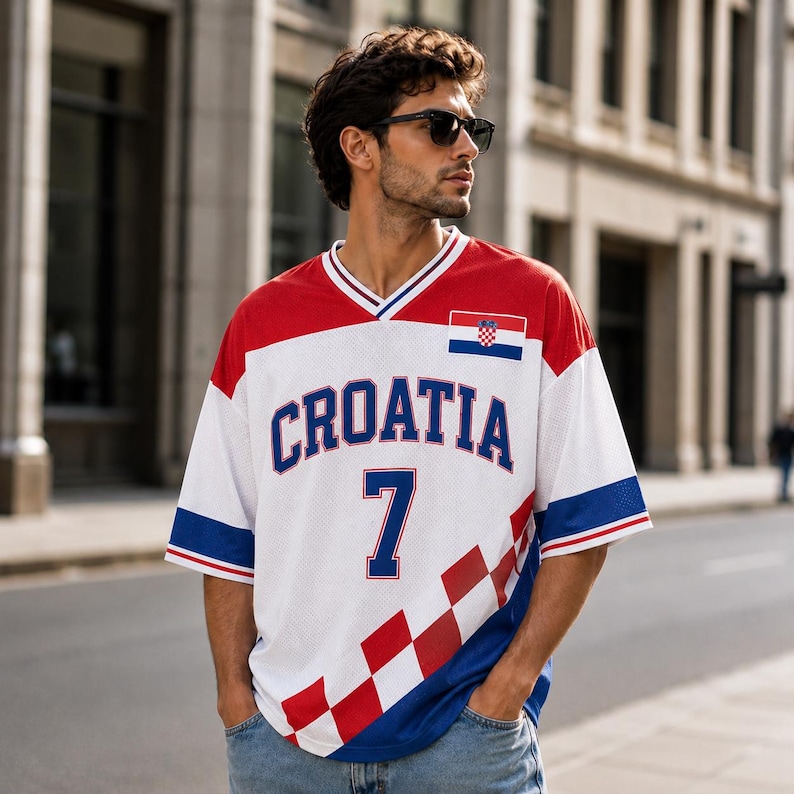 Puede incluir: Una camiseta de malla blanca, roja y azul con el texto CROATIA en letras azul oscuro, el n&uacute;mero 7 en azul oscuro, un peque&ntilde;o parche de la bandera croata en el pecho y un patr&oacute;n de cuadros rojos y blancos en el lado inferior izquierdo y mangas.