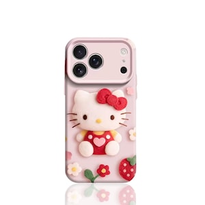 May include: Pink phone case featuring a 3D Hello Kitty design. The case has a raised, textured design of Hello Kitty wearing a red dress and bow, surrounded by flowers and a strawberry. The case has three camera lenses.