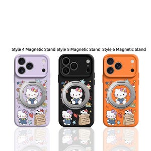 May include: Three phone cases with magnetic stands, featuring Hello Kitty designs. The cases are purple, black, and orange. Each case has a silver ring holder and a cartoon illustration of Hello Kitty. The text "Hello Kitty" is visible.