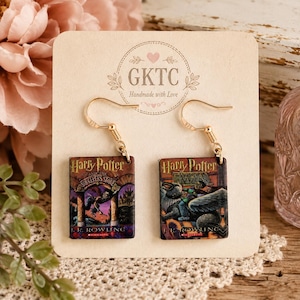 Op de afbeelding: Een paar goudkleurige haak-oorbellen met miniatuur boekomslagen van Harry Potter en de Steen der Wijzen en Harry Potter en de Gevangene van Azkaban. De oorbellen zijn bevestigd op een beige kaart met de tekst GKTC Handmade with Love.