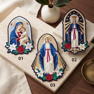 May include: Three embroidered patches featuring religious figures. Patch 01 shows a woman holding a child with white lilies and a red rose. Patch 02 depicts a crowned figure in a blue robe with rays, roses, and lilies. Patch 03 shows a figure with arms outstretched, rays, roses, and lilies.