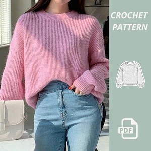 May include: A pale pink, ribbed knit jumper with long sleeves. The image also includes a PDF icon and the words "CROCHET PATTERN". The jumper is paired with high-waisted blue jeans.