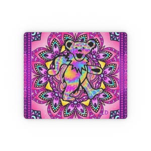 Könnte beinhalten: Rechteckiges Mauspad mit einem Batik-Bären-Motiv auf einem Mandala-Design. Der Bär ist in Gelb-, Orange-, Rosa-, Blau- und Lilatönen gehalten. Das Mandala hat rosa, lila, gelbe und türkisfarbene Akzente. Der Rand ist dunkelrosa mit einem sich wiederholenden Muster.