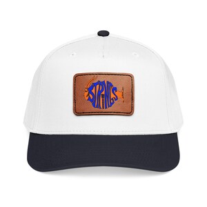 Può includere: Cappellino da baseball bianco con visiera blu navy e toppa in pelle marrone. La toppa presenta la parola "STRINGS" in blu, disegnata a forma di pesce con accenti arancioni. Il cappellino ha un bottone nero in alto.