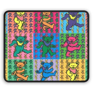 May include: A colorful mousepad featuring a grid of dancing bears in various vibrant colors. Each bear has a unique color scheme, including yellow, orange, green, blue, purple, and pink. The background of each square is filled with smaller bear patterns.
