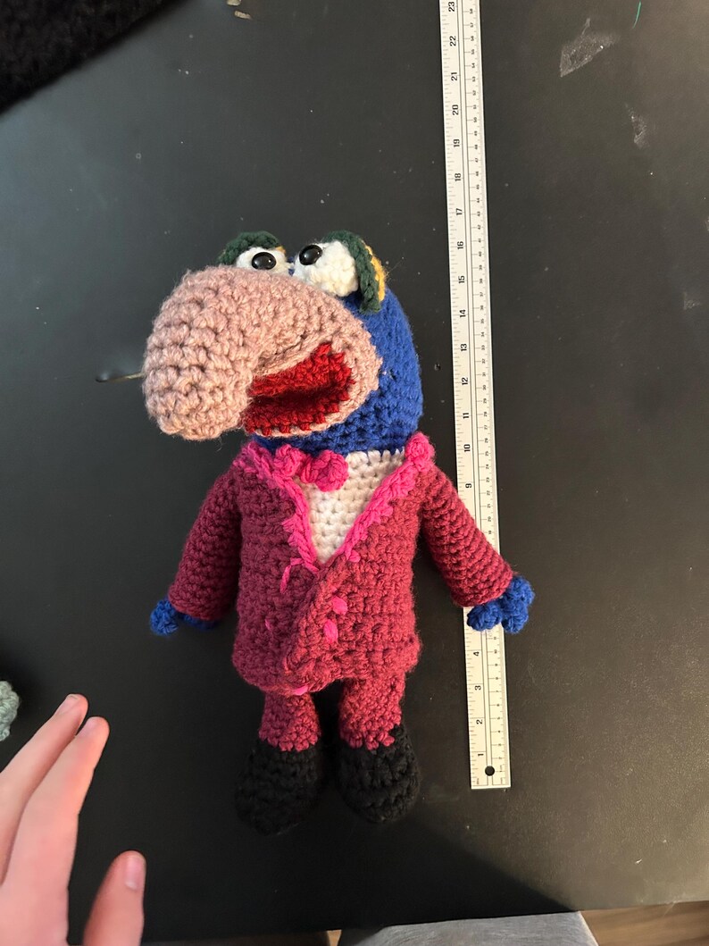 Pu&ograve; includere: Bambola all'uncinetto fatta a mano di un personaggio dei Muppet, con naso rosa, testa blu e abito rosso con papillon bianco. La bambola ha scarpe nere e mani blu. La bambola &egrave; alta circa 25 cm.
