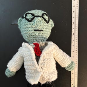 Pu&ograve; includere: Bambola all'uncinetto fatta a mano di uno scienziato, con testa verde chiaro, occhiali neri, camice bianco e cravatta rossa. La bambola ha scarpe nere ed &egrave; alta circa 18 cm.