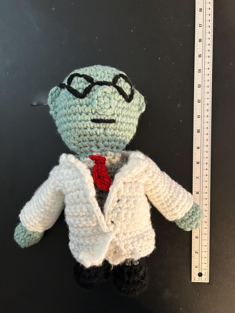 Pu&ograve; includere: Bambola all'uncinetto fatta a mano di uno scienziato, con testa verde chiaro, occhiali neri, camice bianco e cravatta rossa. La bambola ha scarpe nere ed &egrave; alta circa 18 cm.