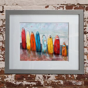 May include: A framed painting depicting a row of colourful surfboards lined up on a beach. The surfboards are painted in shades of red, yellow, blue, and green. The painting is signed "Nicclectic" in the bottom right corner.