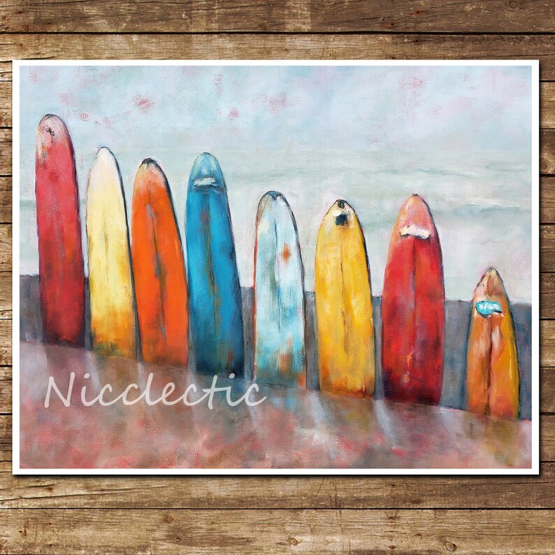 May include: A painting depicting eight colourful surfboards arranged on a sandy beach. The surfboards are painted in shades of red, orange, yellow, blue, and green. The background is a hazy blue sky.